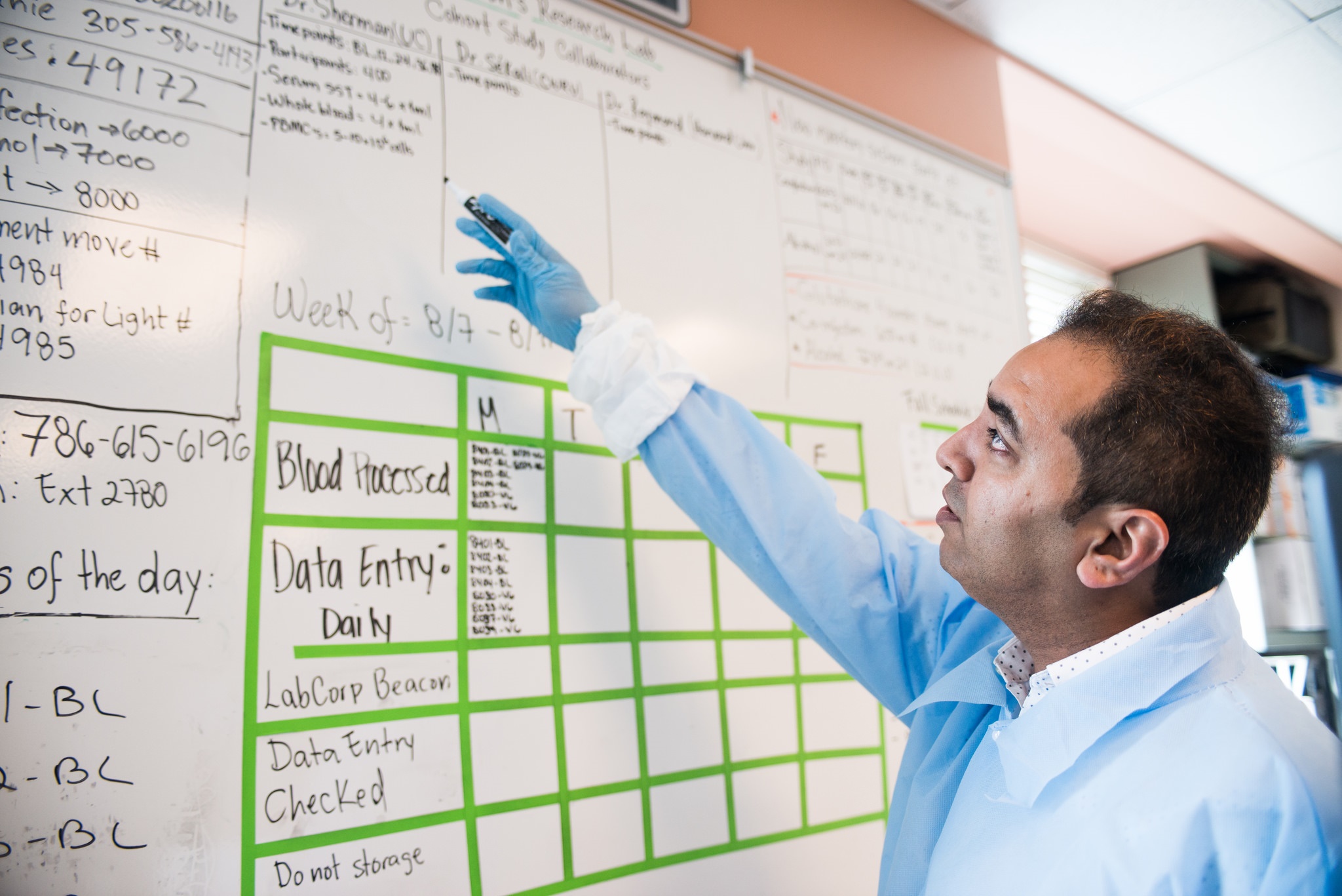 Researcher pointing at board that has statistics listed on it